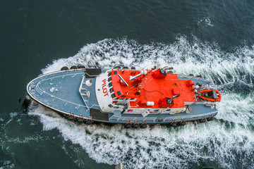 Canvas Print - An Orange and White Pilot Boat From Above Cutting Through Water.