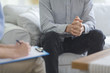 Psychologist taking notes during psychotherapy session with man