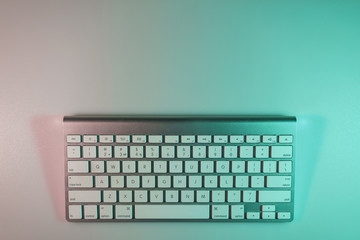 Poster - Beautiful modern silver keyboard in the color light on a table and night background. Top view.