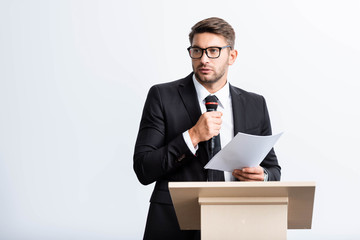 Wall Mural - businessman in suit standing at podium tribune and speaking during conference isolated on white