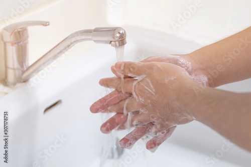 Fotomural A man washed his hands with soap in a sink.