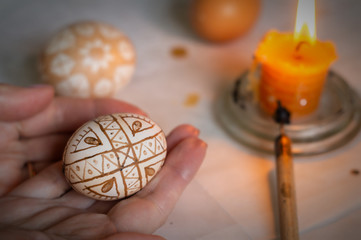 Easter egg painted with hot wax in a female hand