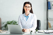 © LIGHTFIELD STUDIOS - beautiful smiling doctor sitting in clinic office with laptop