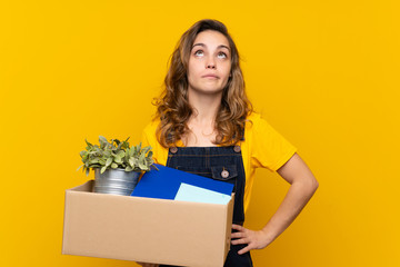 Wall Mural - Young blonde girl making a move while picking up a box full of things making doubts gesture while lifting the shoulders