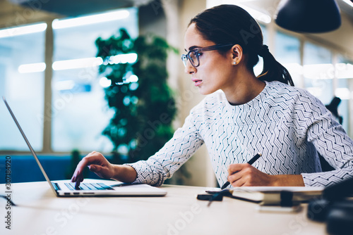 Fotomural Serious female secretary reading information making booking on web page on lapto