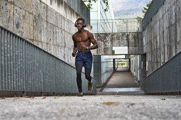 Wall Mural - Athletic man is running near the grey wall