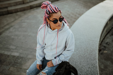 city portrait of handsome hipster girl with colored afro braids wearing gray blank hoodie or hoody w