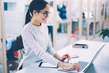 Smiling female manager working on reception in clinic satisfied with feedbacks from clients checking mail on netbook,administrative woman completed report reading information standing on desktop