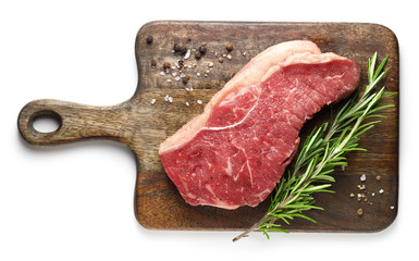 Wall Mural - fresh raw beef steak on wooden cutting board with spices and rosemary isolated on white background