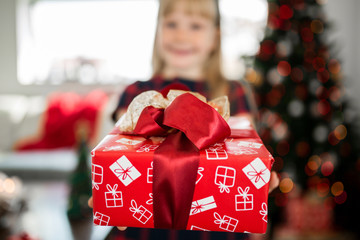 Wall Mural - Young girl holding red christmas present