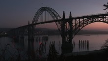 Beautiful Shot Of The Yaquina Bay Bridge In Newport, Oregon At Sunset Silhouetted In The Purple Darkening Sky Camera Pans Right Framing The Arch Structure