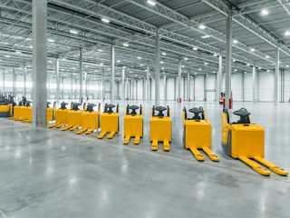 a lot of trucks standing in a row in a big, empty warehouse. the parade of trucks. new technology for a warehouse.