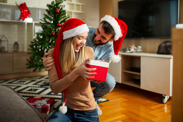 Young man surprising his girlfriend with Christmas gift