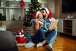 © Novak - Love couple with Christmas hat on head using tablet and credit card to buying online