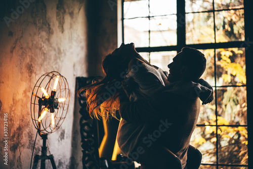 Cuadros en Lienzo Young man holding woman in his hands. Couple in love at the home.