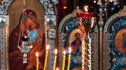 Wax burning candles in an orthodox church on the icon background.