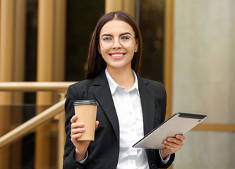 Poster - Beautiful young businesswoman with coffee and tablet computer outdoors