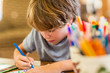 © Mint Images - 6 year old boy drawing amoung colorful pens