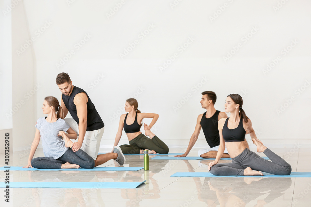 Group of people practicing yoga with instructor in gym