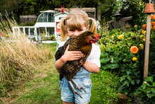 Portrait Of Girl Holding Chicken In Garden
