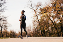 Black Athletic Woman Jogging In Autumn Day At The Park.