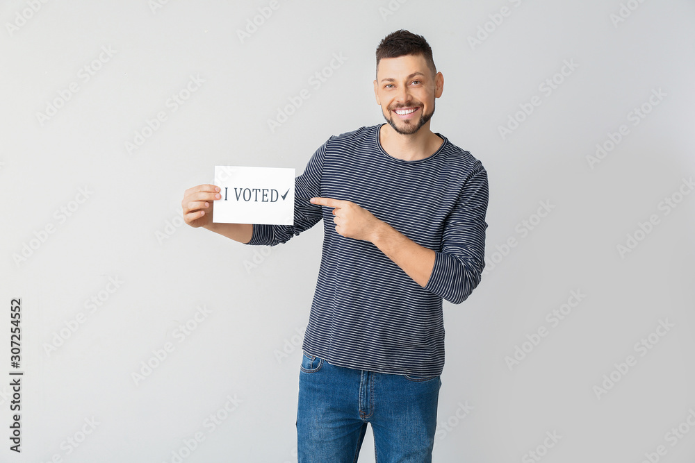 Man holding paper with text I VOTED on light background