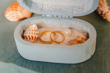 wedding rings in a rustic box with white sand and seashells, for the wedding ceremony or vow renewal