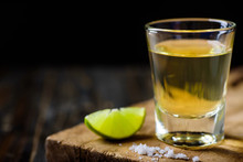 Tequila in a shot glass on a brown wooden background prepared for a party