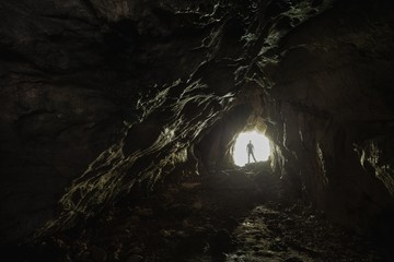 Wall Mural - Person standing at the enlightened white exit of the dark tunnel - life starts blooming concept