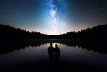 Romantic Couple Standing Under The Starry Sky, Milky Way Reflects Off Lake