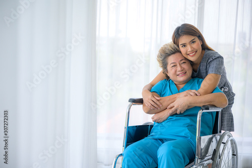 Asian daughter or care assistant helping support senior woman or mother