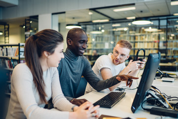 Diverse group of students discussing project in library