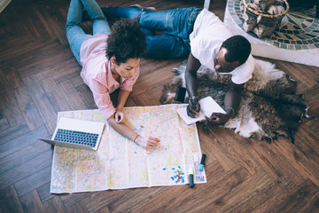 Black man and woman making notes on map at home