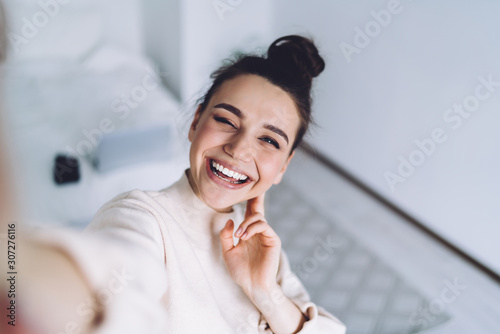 Cuadros en Lienzo Attractive young woman using camera of smartphone taking sunny selfie at home