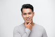 © makistock - Happy smiling young handsome Asian man face with hand touching chin studio shot isolated