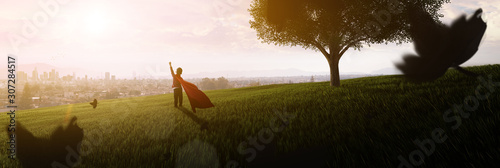 Fotomural boy dreaming of being superhero in the park looking at the city