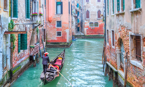 Fotografía Venetian gondolier punting gondola through green canal waters of Venice Italy