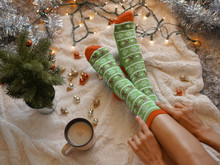 Feet In Christmas Socks Near The Christmas Tree