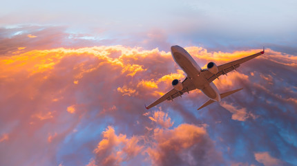 Wall Mural - Airplane in the sky at sunset clouds