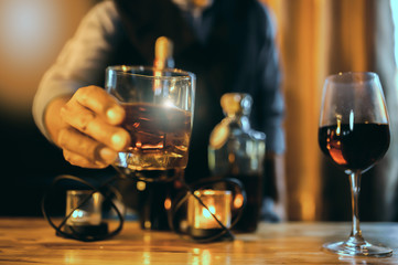 Wall Mural - Hands of a bartender, with a glass of whiskey, soft focus.