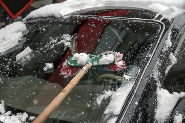 Wall Mural - Man cleaning snow from car with brush.