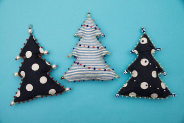 3 Handmade  polka dot  and striped  textile fabric naive retro style Christmas tree ornament decorated with beads on blue background