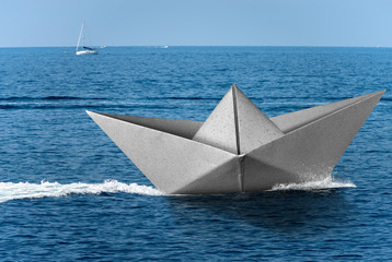 Wall Mural - White paper boat runs fast over the blue sea with wake, in the background the horizon with the sky