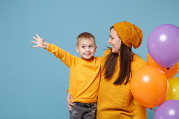 Wall Mural - Woman in yellow clothes have fun with cute child baby boy 4-5 years old celebrating birthday holiday party with colorful air balloons. Mommy son isolated on blue background. Family childhood concept.