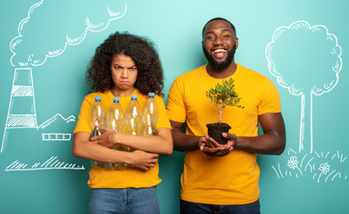 Wall Mural - Pollution versus nature. Girl unhappy with plastic garbage and boy happy with a small tree. Save the World concept
