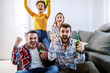 © Dusan Petkovic - Group of friend sitting in living room and cheering for their favorite football team. They all holding beer bottles.
