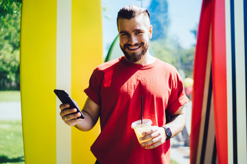 Content young male in casual wear browsing smartphone on sunny day