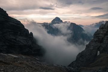 Sunset view on Triglav summit in clouds, in Julian Alps, Slovenia after hike on Jubilee via ferrata, hut Koča na Kredarici visible