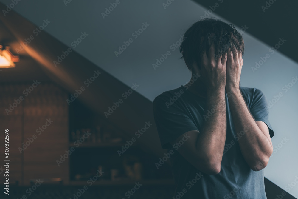 Depressed man is crying by the window of kitchen loft - obrazy, fototapety, plakaty 