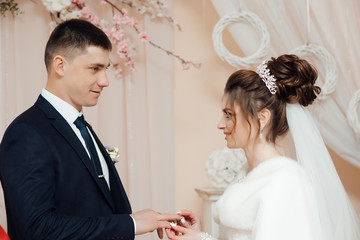 Two lovers hearts on the wedding ceremony. Stylish happy smiling newlyweds. Bride and groom look at each other at a wedding ceremony. Rings. The bride wears the ring groom. 